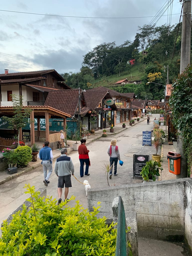 Rua da Vila de Maringá com restaurantes, lojas e pessoas caminhando, em Visconde de Mauá