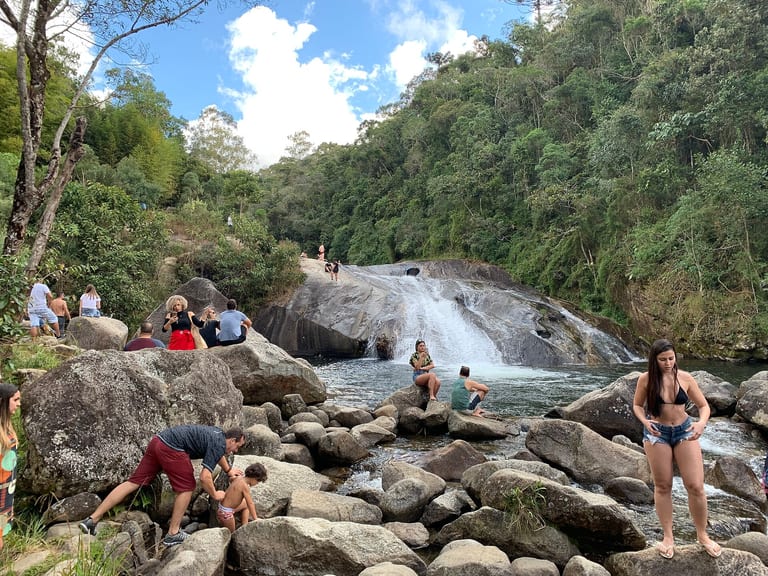 Cachoeira do Escorrega com o tobogã de pedra, o poço e banhistas nas pedras, no alto da Vila da Maromba, em Visconde de Mauá