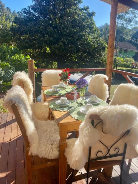 Café da manhã posto na varanda com cadeiras cobertas de pele de carneiro, Pousada do Figa