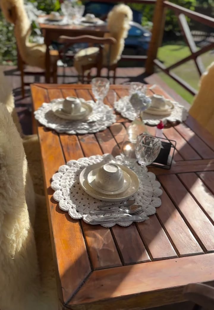 Mesa do café da manhã posta na varanda da Pousada do Figa, com o jardim ao fundo