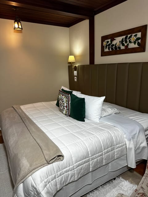 Suíte 2 da Pousada do Figa à noite, com luz da luminária sobre a cama king arrumada
