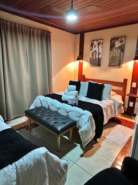 Quarto Triplo da Pousada do Figa com cortina de linho, quadros e toalhas sobre a cama