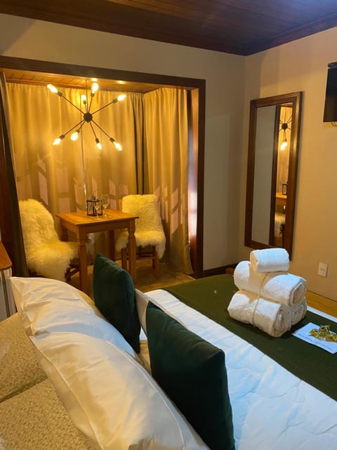 Canto do Quarto Triplo da Pousada do Figa com mesa para dois, poltronas de pele e lustre