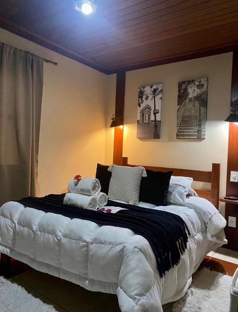 Cama de casal do Quarto Triplo da Pousada do Figa com manta preta e toalhas enroladas