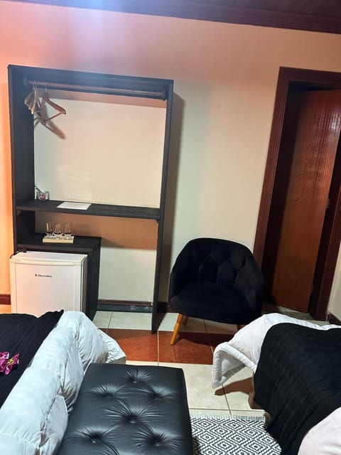 Frigobar, arara e poltrona do Quarto Triplo da Pousada do Figa